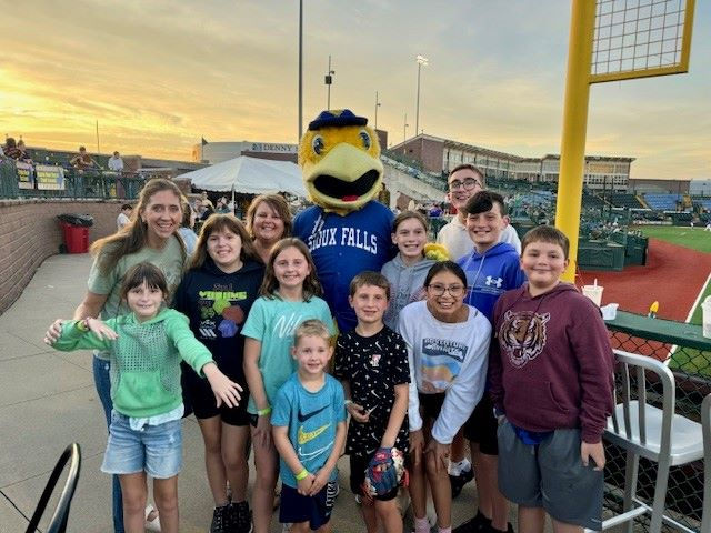 SDDeaf Students on a summer night outing with the Sioux Falls canary mascot. Background is the Sioux Falls baseball stadium.