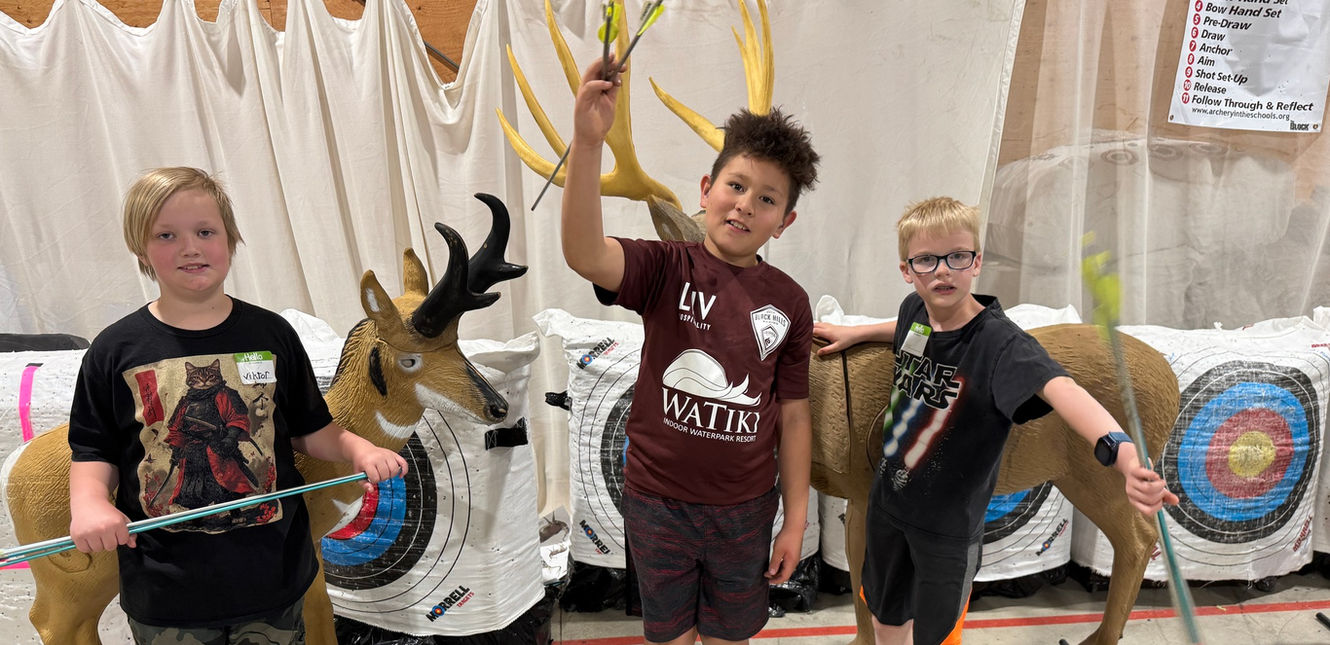 Three children holding arrows in front of deer targets at an SDSD event