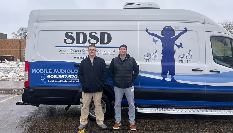 2 adult male SDDeaf staff standing in front of the SDDeaf mobile audiology clinic.