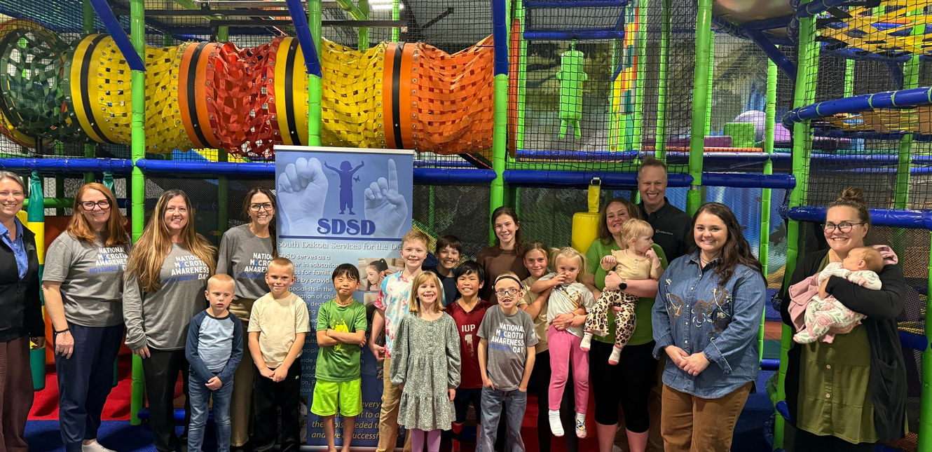 Group of adults and children at an indoor playground at a microtia event